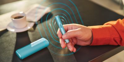 User holding an IQOS ILUMA i Prime device while performing troubleshooting steps