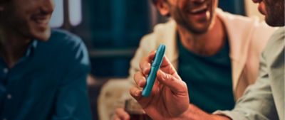 Men holding IQOS Originals Duo holder in turquoise color.