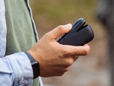 Eine Hand hält ein schwarzes IQOS ORIGINALS DUO Gerät und öffnet es.