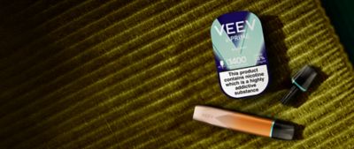 VEEV inPRIME Classic Mint package and amber VEEV inPRIME vaping device and pod on a green fabric