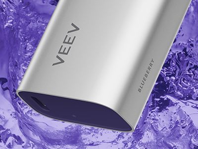 Primer plano de la parte inferior del dispositivo de vapeo VEEV NOW sobre un fondo naranja