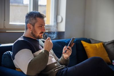 Man on phone using a vape 