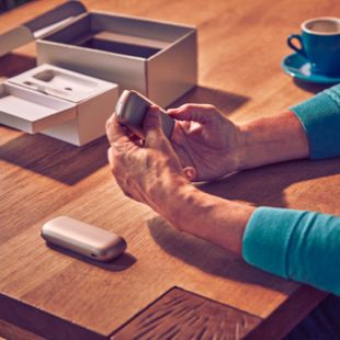 Man with the IQOS Duo in his hand and a cup of coffee on the table