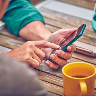 Man checking his phone with the IQOS device on the table