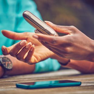 A boy and a girl talk with a gold IQOS DUO in her hand