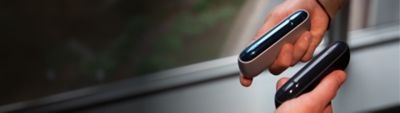 Zwei Personen halten IQOS ORIGINALS Geräte in Silver und Slate mit personalisierten Klappen-Covern.