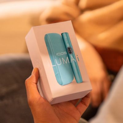 How to use IQOS ILUMA i desktop banner - device in its packaging box being held by user