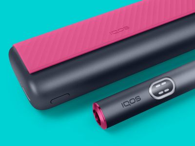 Pocket charger dan holder IQOS ILUMA i Prime dalam tampilan dekat dengan latar biru.