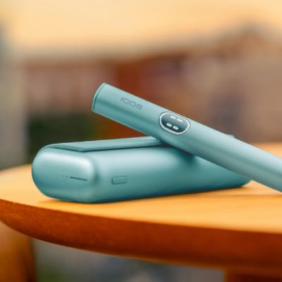 Pocket charger dan holder IQOS ILUMA i Prime ditampilkan di atas meja siap untuk penggunaan pertama.