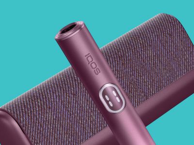 Warranty cards IQOS ILUMA i PRIME - close-up of IQOS ILUMA i Prime holder on top of pocket charger with a blue background