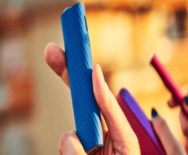 An IQOS ILUMA ONE device in a person's hand.