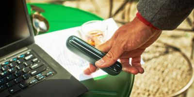 A passport, plane ticket, and IQOS device on a desk.