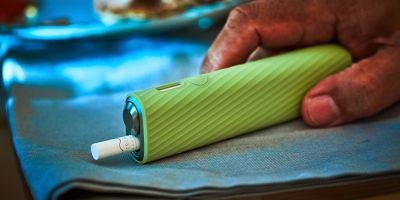 Hands holding an unopened IQOS device box.