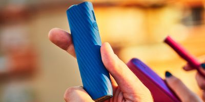 Two people holding phones over two cups of coffee.