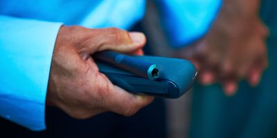 Hands unboxing an IQOS device.