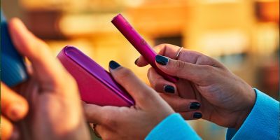 Two people holding phones over two cups of coffee.