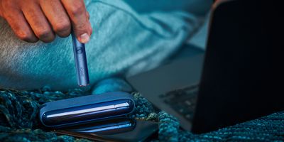 Hands holding a Pebble Beige IQOS ILUMA device.