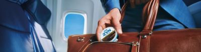 Man pulling out a ZYN can from his bag in the plane