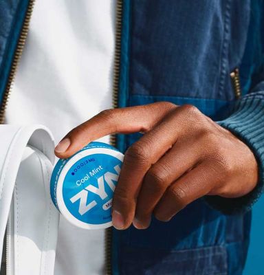 Hand holding a can of blue ZYN Cool Mint nicotine pouches