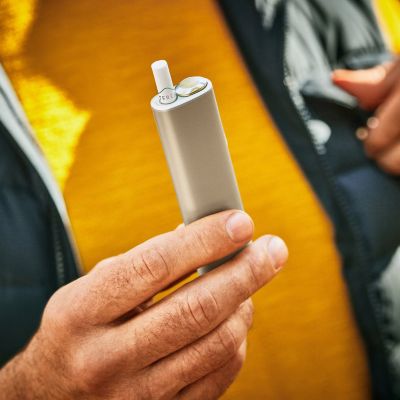 A bearded man using an Obsidian Black IQOS ILUMA PRIME device. 