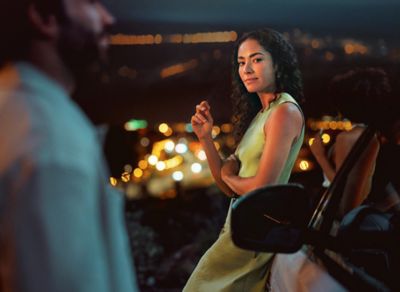 Женщина в зеленом платье стоит рядом с мужчиной у машины