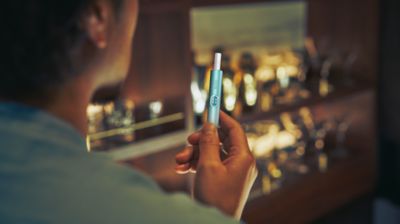 A man holding IQOS Iluma holder with a TEREA heated tobacco stick