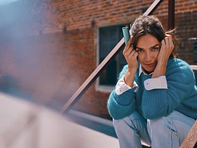 Mujer sosteniendo un IQOS ILUMA i ONE color Breeze Blue