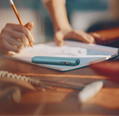 IQOS ILUMA i ONE color breeze blue sobre un cuaderno