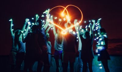 Skupina lidí držící světelný řetěz, uprostřed světelné srdce.