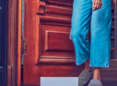 Jemand in blauer Jeans steht in einer offenen Tür vor einem Paket