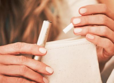 Jemand hält ein IQOS ILUMA Gerät und einen TEREA Tabakstick in der Hand