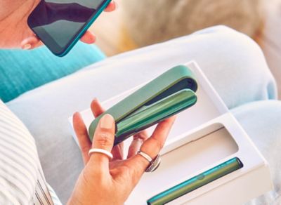 Jemand mit großen Ringen am Finger nimmt ein IQOS ILUMA Device aus seiner Verpackung