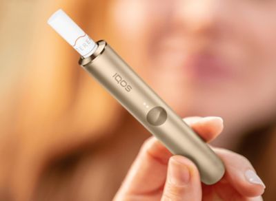 Eine Hand hält ein IQOS ILUMA mit eingesetztem TEREA Tabakstick