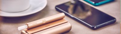 IQOS ILUMA Prime Charger auf einem Tischtuch