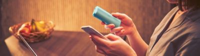 Person hält Smartphone und IQOS Kit in der Hand.
