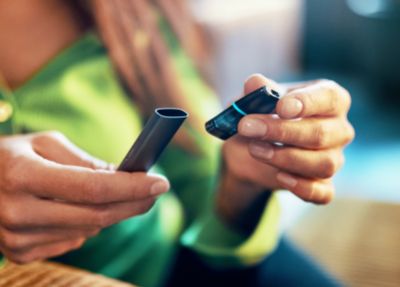 Jemand in einem grünen Pullover setzt einen Pod in ein VEEV ONE Device