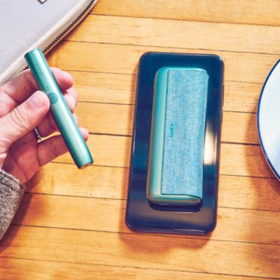 IQOS ILUMA Holder und Charger auf einem Holztisch