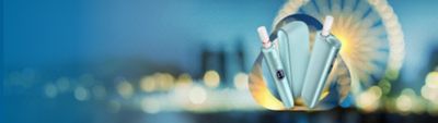 Drei IQOS ILUMA i vor einem unscharfen Hintergrund mit leuchtenden Lichtreflexen