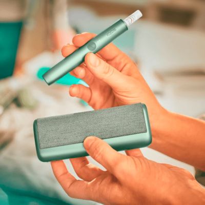 Jemand hält einen jadegrünen IOQS ILUMA PRIME Holder und Pocket Charger in den Händen.