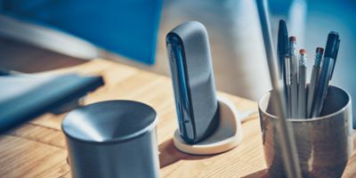 Ein Tisch auf dem ein IQOS ILUMA in einer Ladestation angebracht ist.