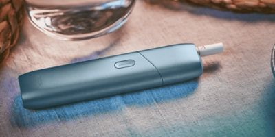 Blau schimmerndes IQOS Originals One auf einem Tisch.