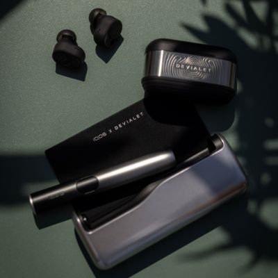 Set IQOS x DEVIALET zariadenia a slúchadiel položený na stole.