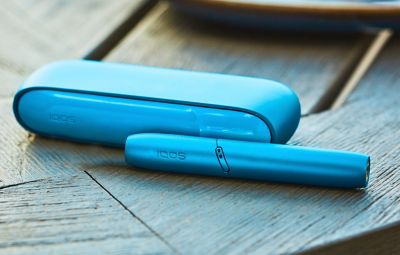 Appareil IQOS bleue posé sur une surface claire