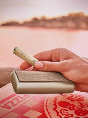 A Golden Khaki IQOS ILUMA PRIME in a person's hand.