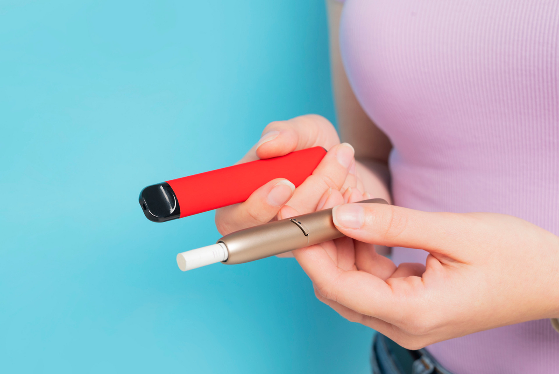 image of person holding a disposable vape and iqos device