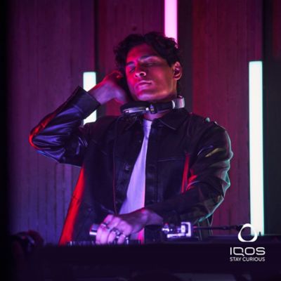 A DJ in the rhythm of their music with an IQOS in hand