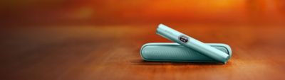 Iqos Iluma I couleur aigue-marine sur fond orange.