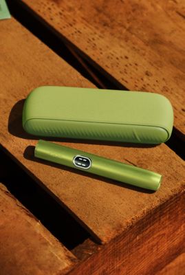 Iqos Iluma i couleur vert anis sur table en bois.