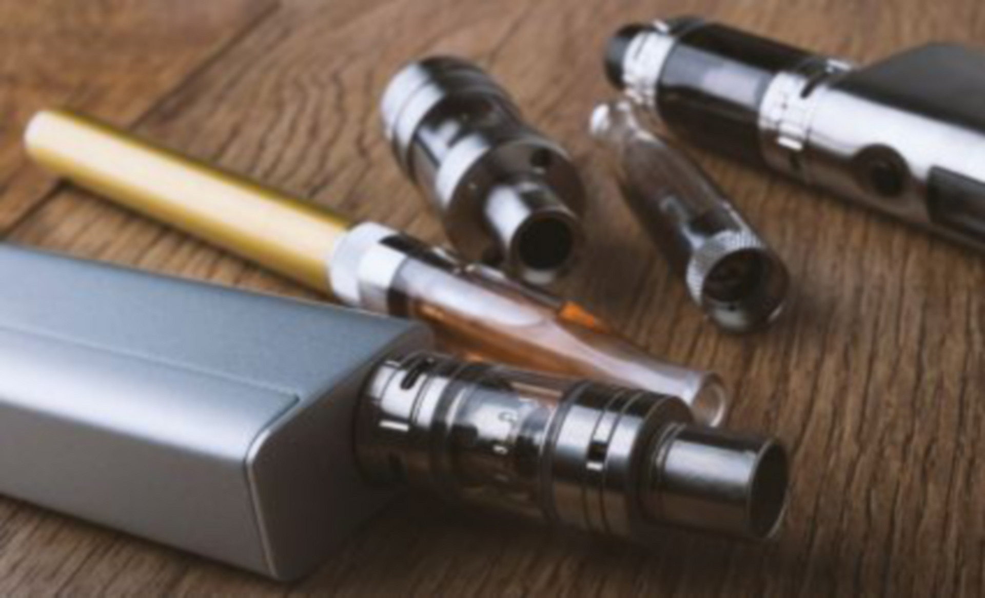A variety of e-cigarette devices on a wooden table