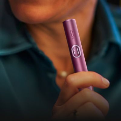 Person hält ILUMA i Tabakerhitzer in der Farbe Digital Violet in der Hand.